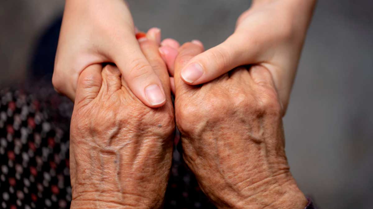 Manos de una persona mayor sostenidas por manos jóvenes, excedencia por cuidado familiar