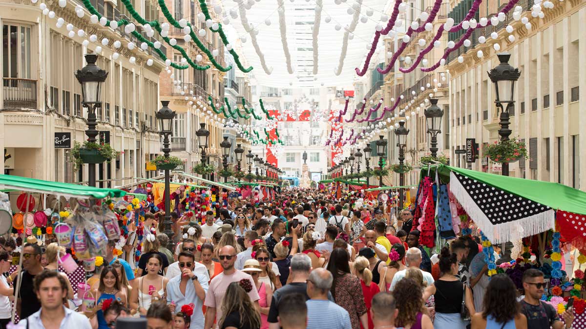 Multitud disfrutando de la Feria de Málaga 2026 en una calle decorada con farolillos