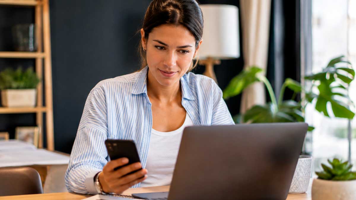 Mujer revisando notificaciones de la Seguridad Social en su móvil y portátil en 2026