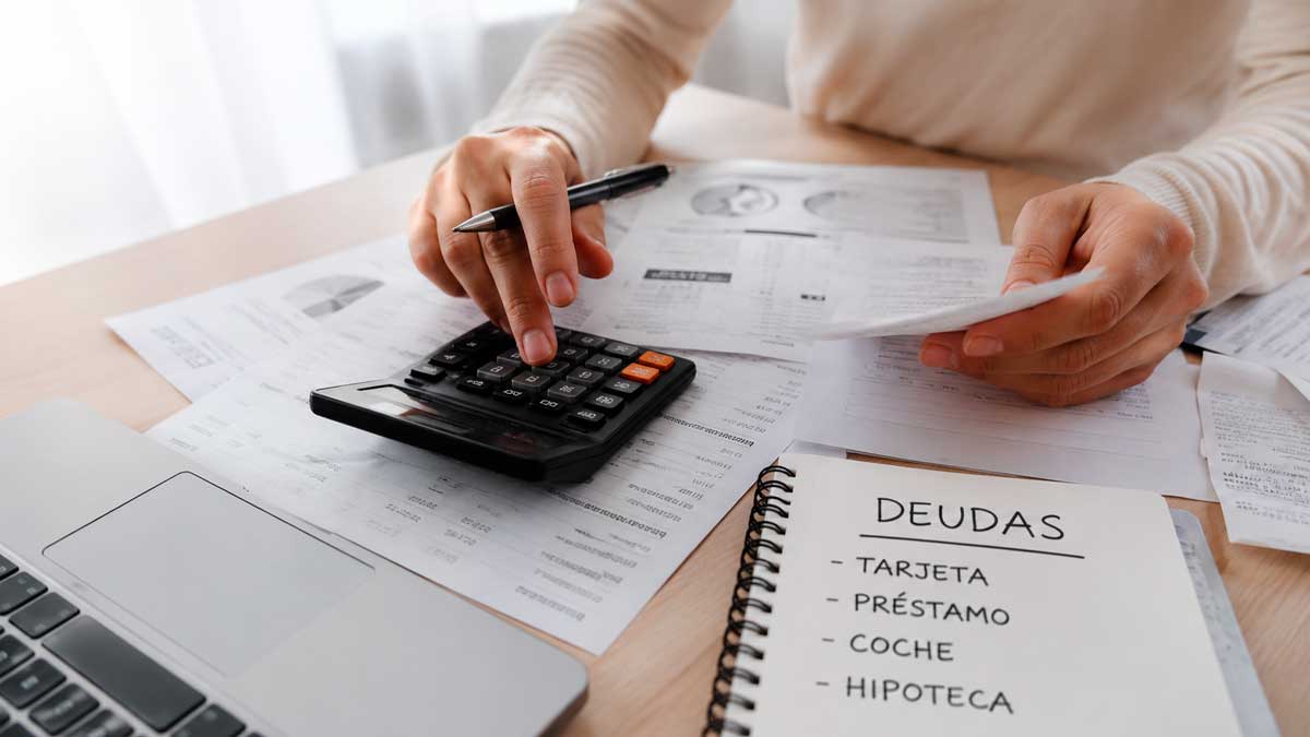 Persona calculando reunificación de deudas en España con documentos y calculadora
