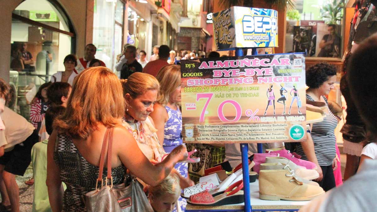 En la imagen se observa a varias personas comprando en una tienda durante la Shopping Night de Almuñécar. El local está decorado con carteles promocionales anunciando descuentos y sorteos, mientras los asistentes exploran los productos y aprovechan las ofertas especiales del evento.