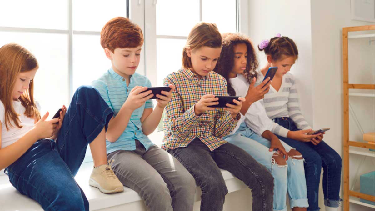 Niños usando móviles y redes sociales sentados juntos, protección de menores