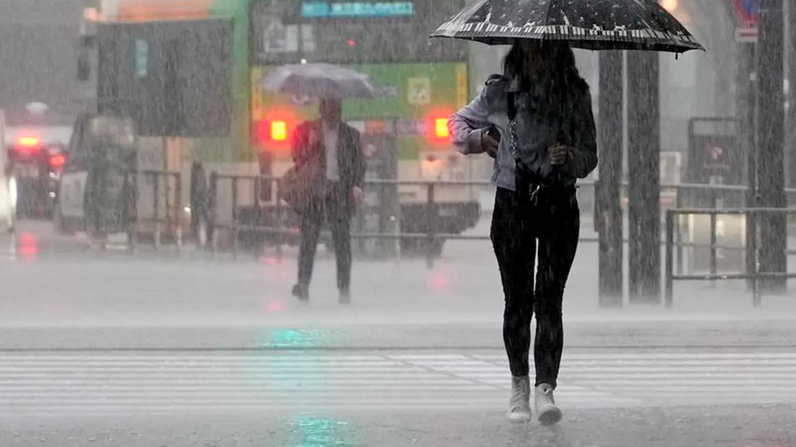 Persona caminando bajo una lluvia intensa con paraguas