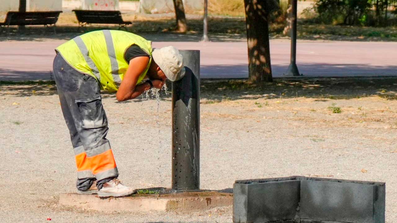 Trabajador se refresca en una fuente durante una jornada de calor en Andalucía