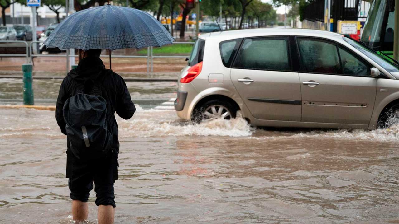 Coche circulando por una calle inundada durante un episodio de fuertes lluvias