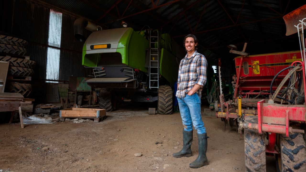 Joven agricultor en una explotación agrícola de Andalucía junto a maquinaria