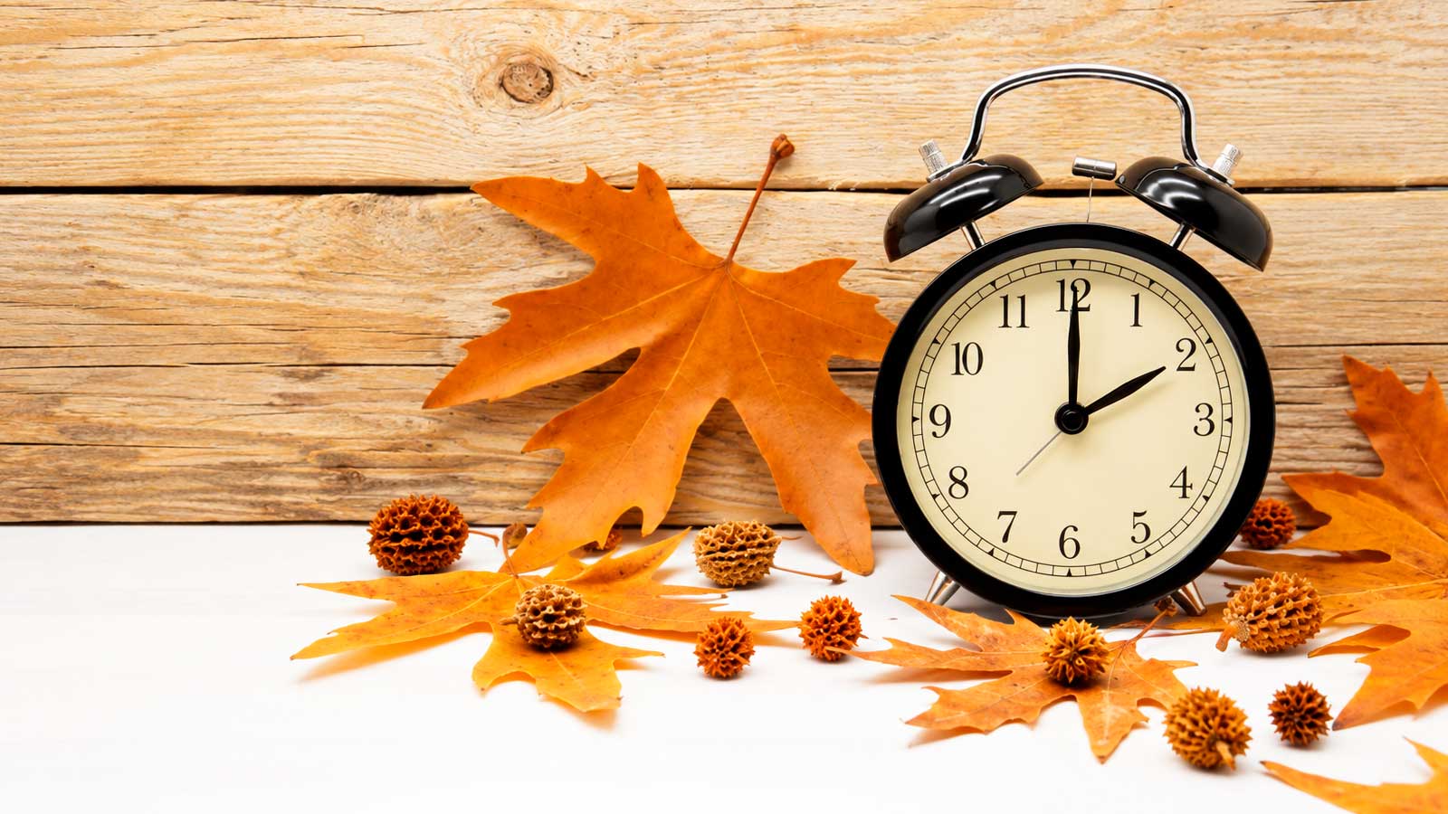 Reloj rodeado de hojas de otoño por el cambio al horario de invierno en España