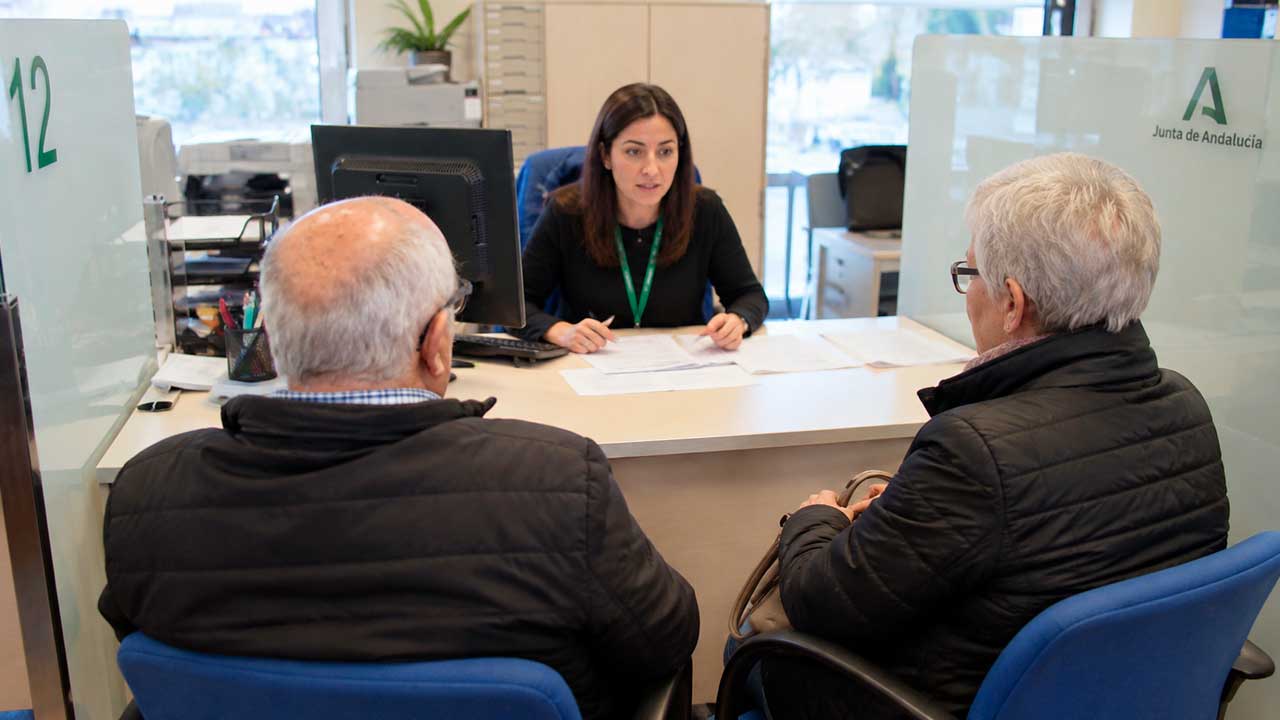 Personas mayores consultando un expediente en una oficina de la Junta de Andalucía