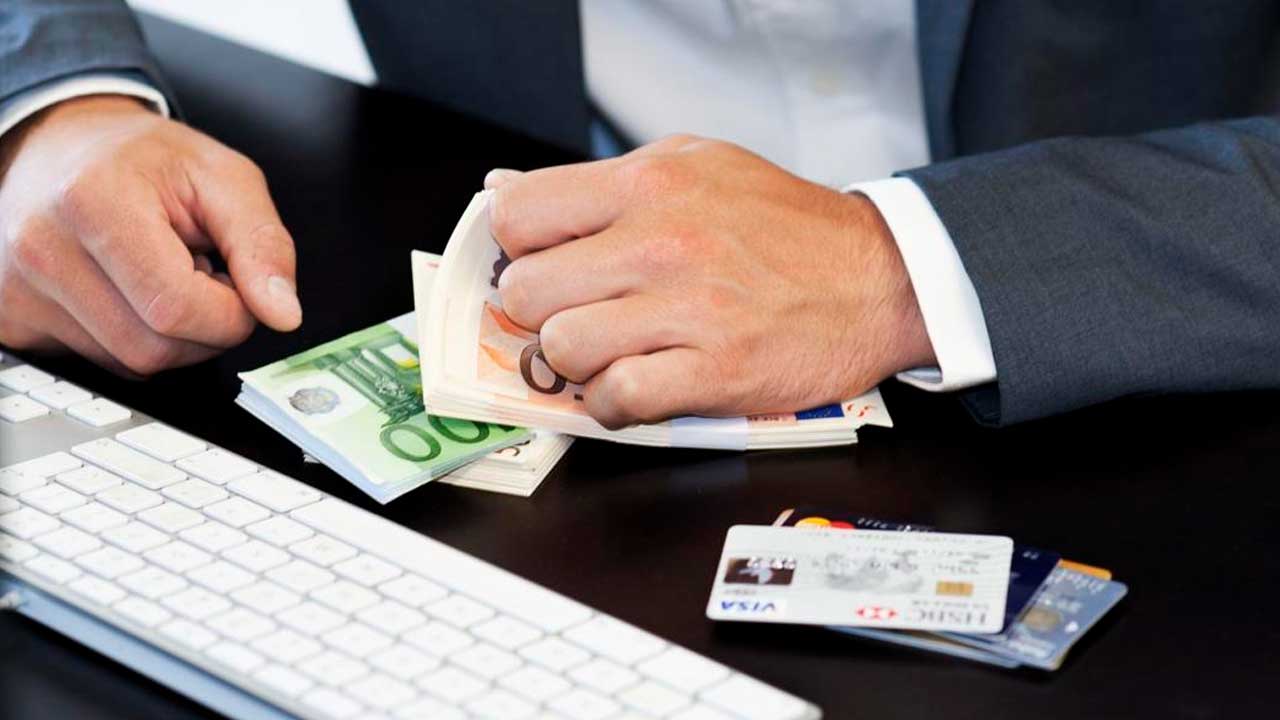 Responsable financiero contando dinero junto a varias tarjetas bancarias en una oficina