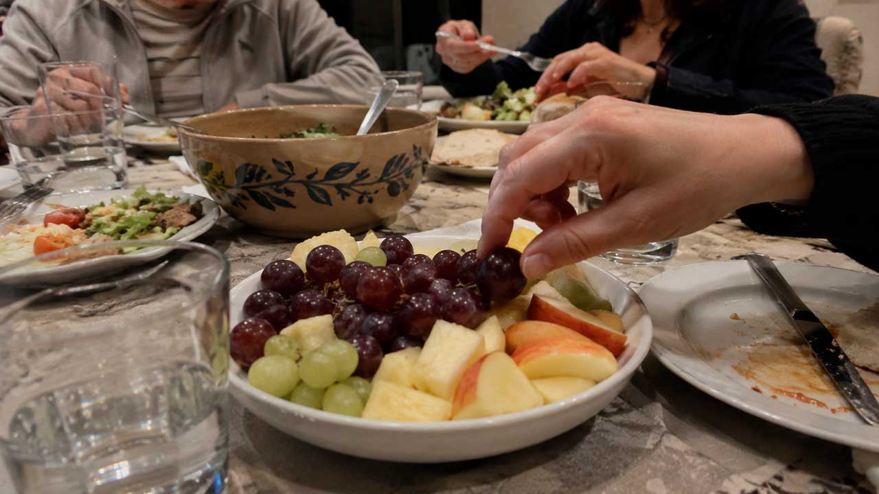 Personas cenando fruta en una mesa familiar durante la noche