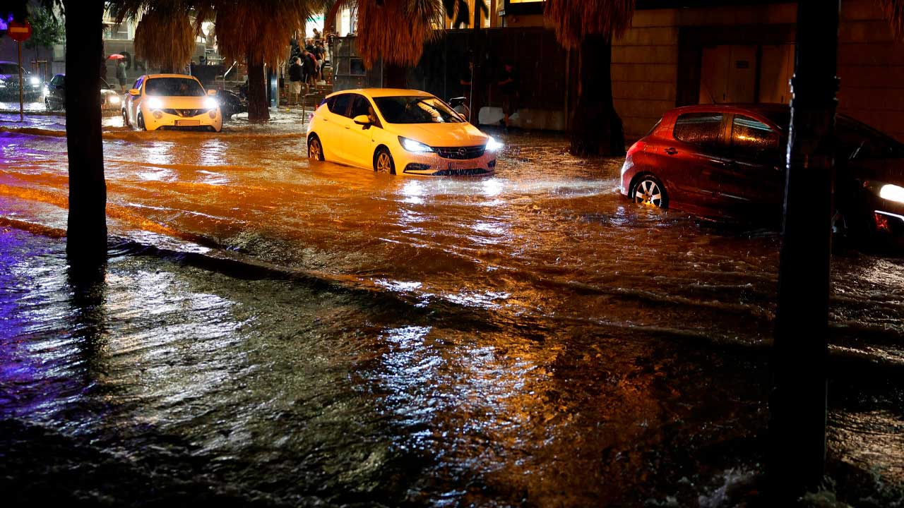 Coches circulando por una calle inundada durante un episodio de fuertes lluvias