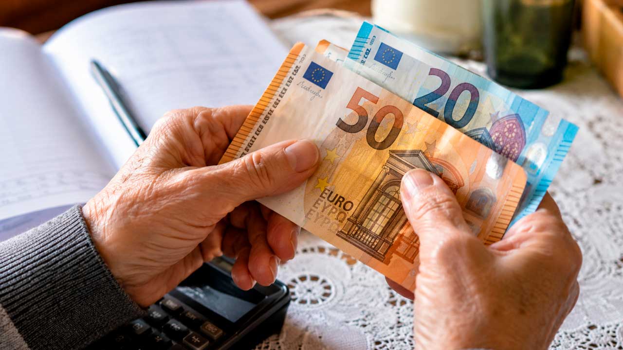 Persona mayor contando billetes de euro en su domicilio