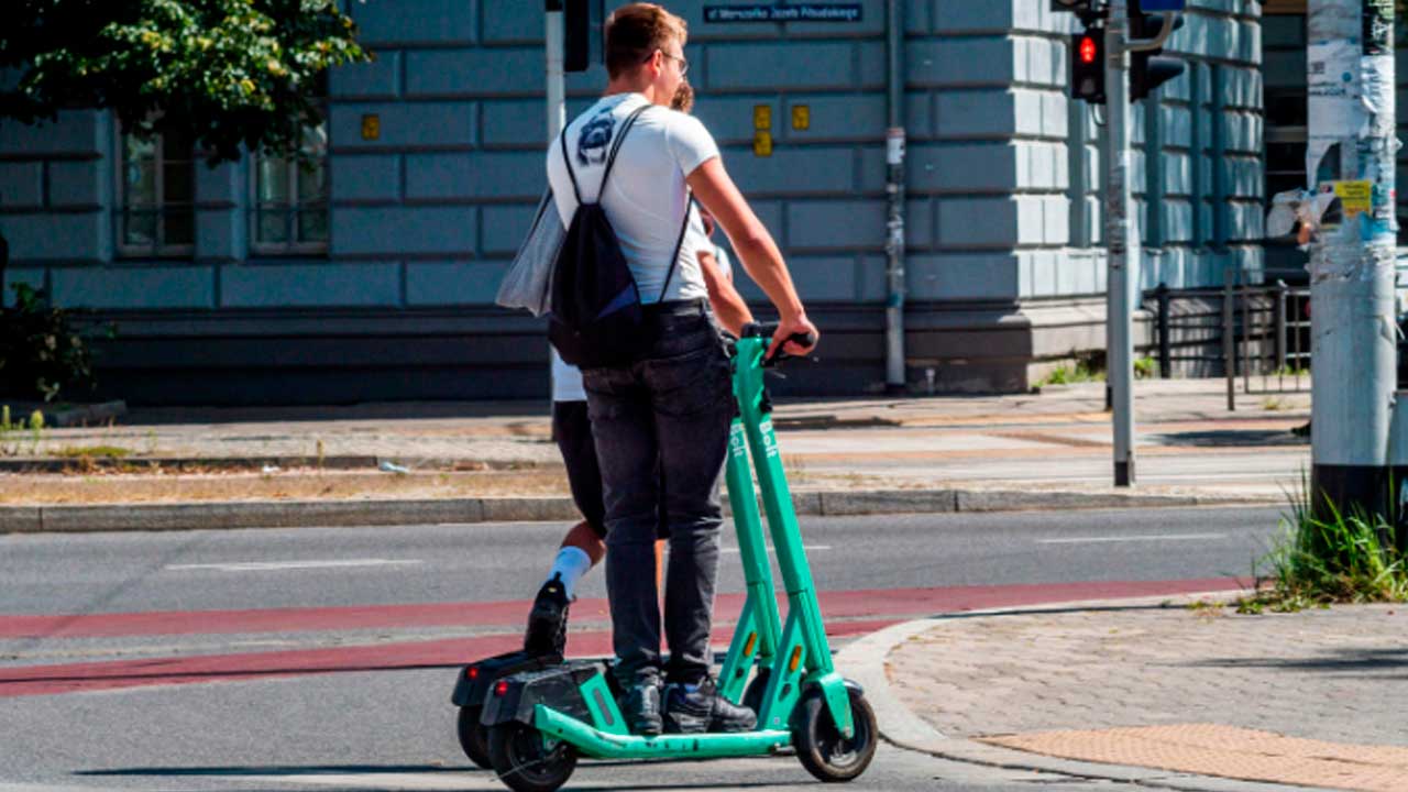 Personas circulando en patinete eléctrico por una vía urbana