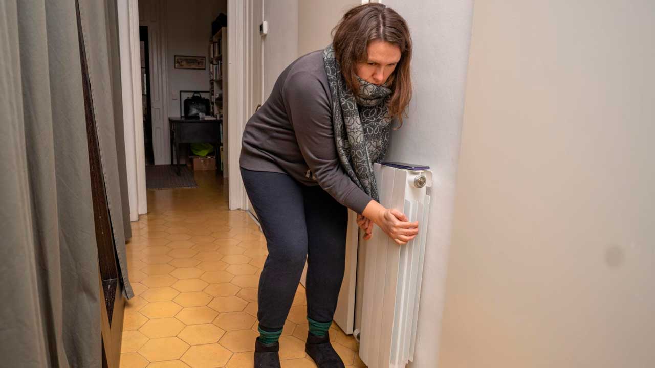 Mujer regulando un radiador de calefacción en una vivienda
