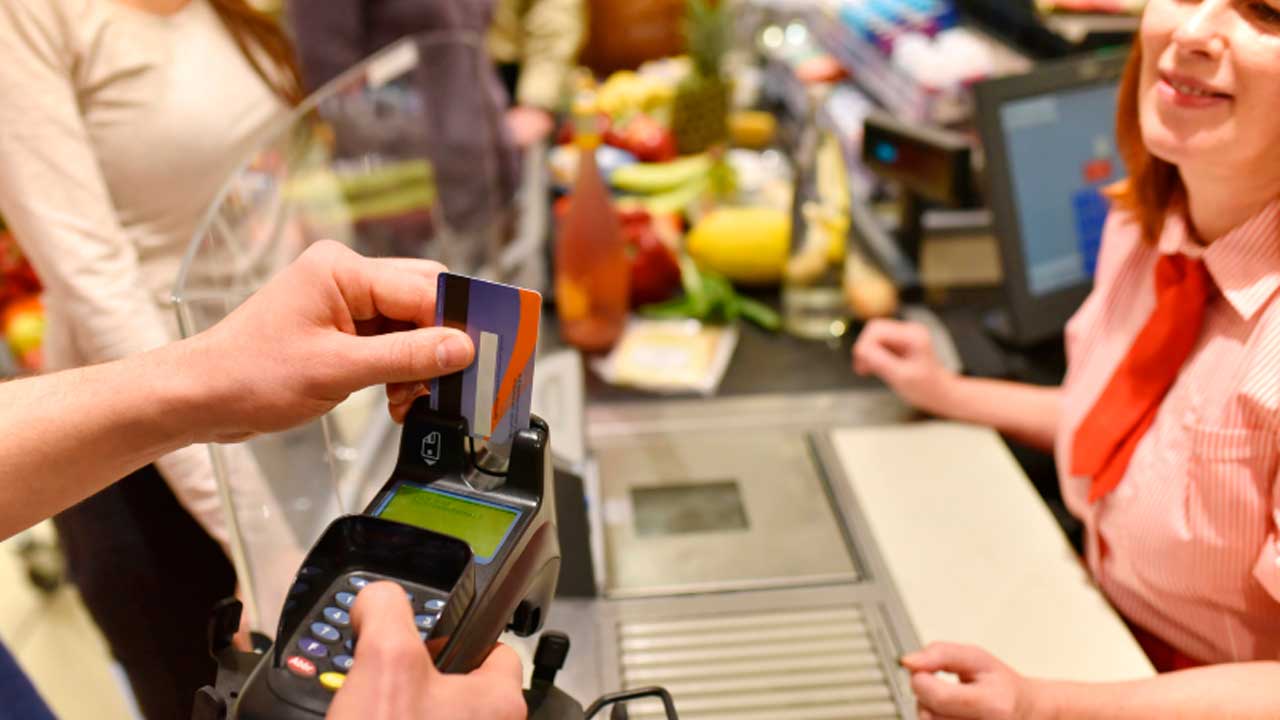 Persona pagando alimentos con tarjeta en la caja de un supermercado
