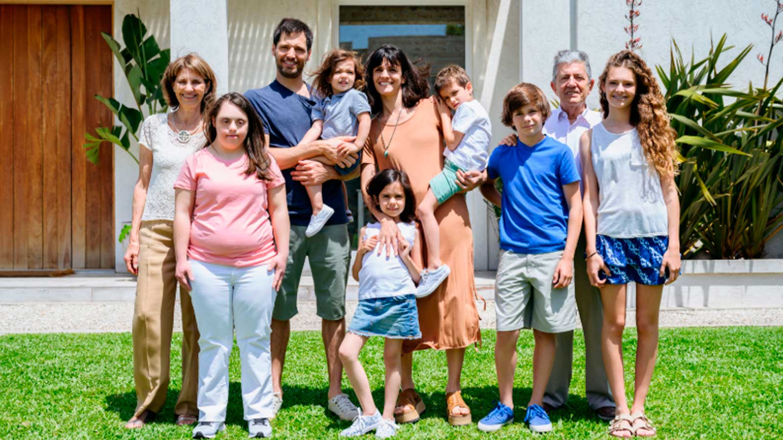Familia numerosa con varios hijos y abuelos delante de una vivienda en Andalucía.