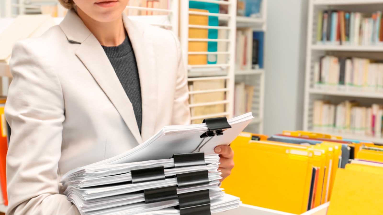 Mujer con documentos administrativos en una oficina, imagen de recurso sobre las 985 plazas de empleo público de la Junta de Andalucía.