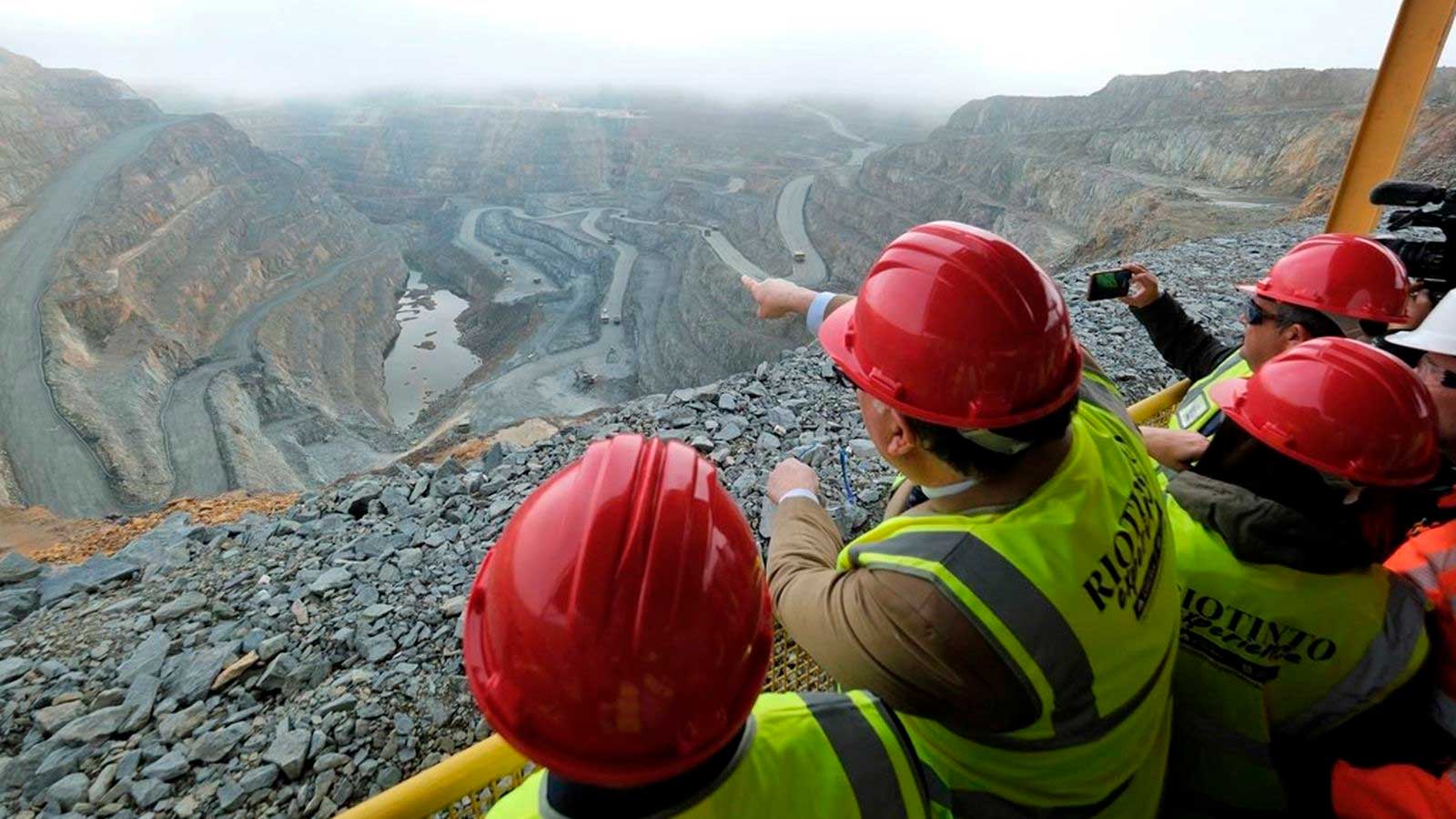 Visitantes con cascos de seguridad contemplan la mina Corta Atalaya en Minas de Riotinto, Huelva.