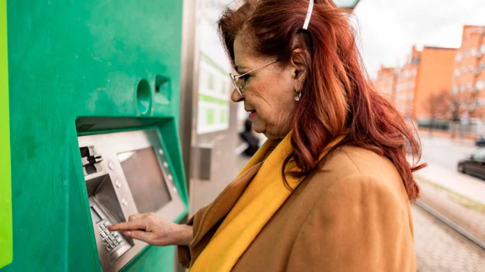 Mujer pensionista utilizando un cajero automático para consultar el pago de su pensión.