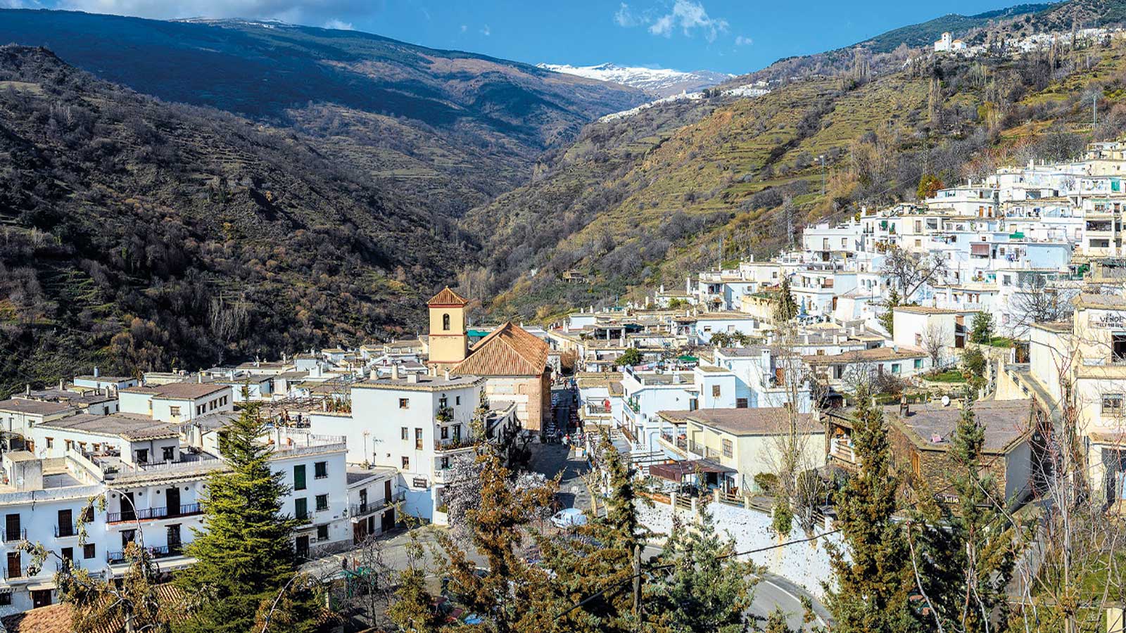 Vista panorámica de Pampaneira, uno de los tres pueblos blancos de la ruta por la Alpujarra de Granada, con Sierra Nevada al fondo.