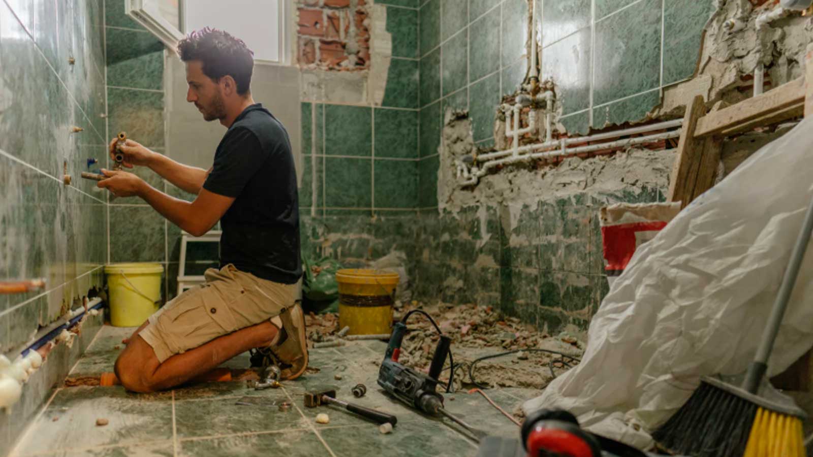 Trabajador reformando un baño antiguo, una de las obras previstas en las ayudas de hasta 10.000 euros para viviendas municipales de Cádiz.