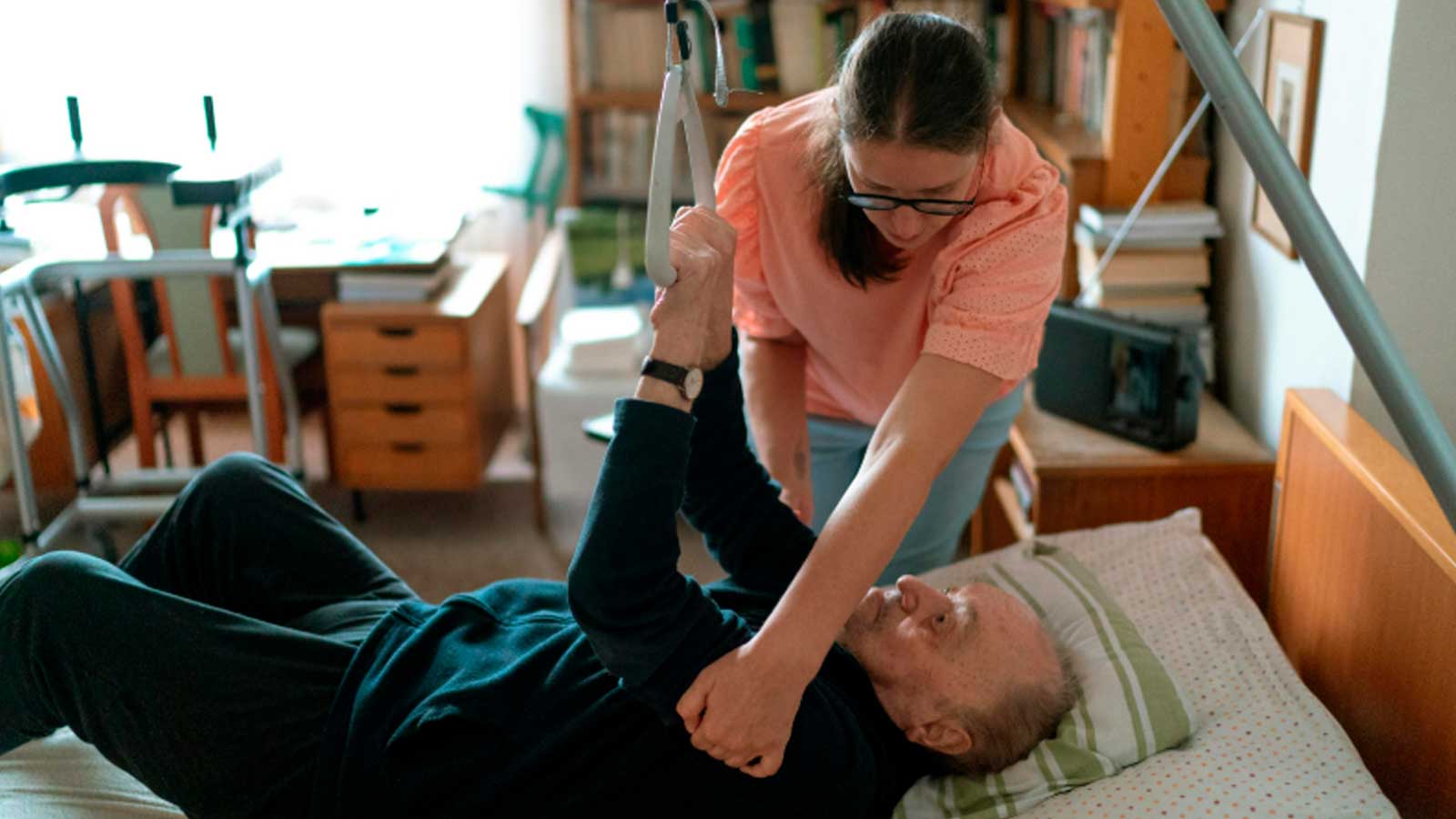 Auxiliar de ayuda a domicilio ayuda a una persona mayor a incorporarse de la cama.